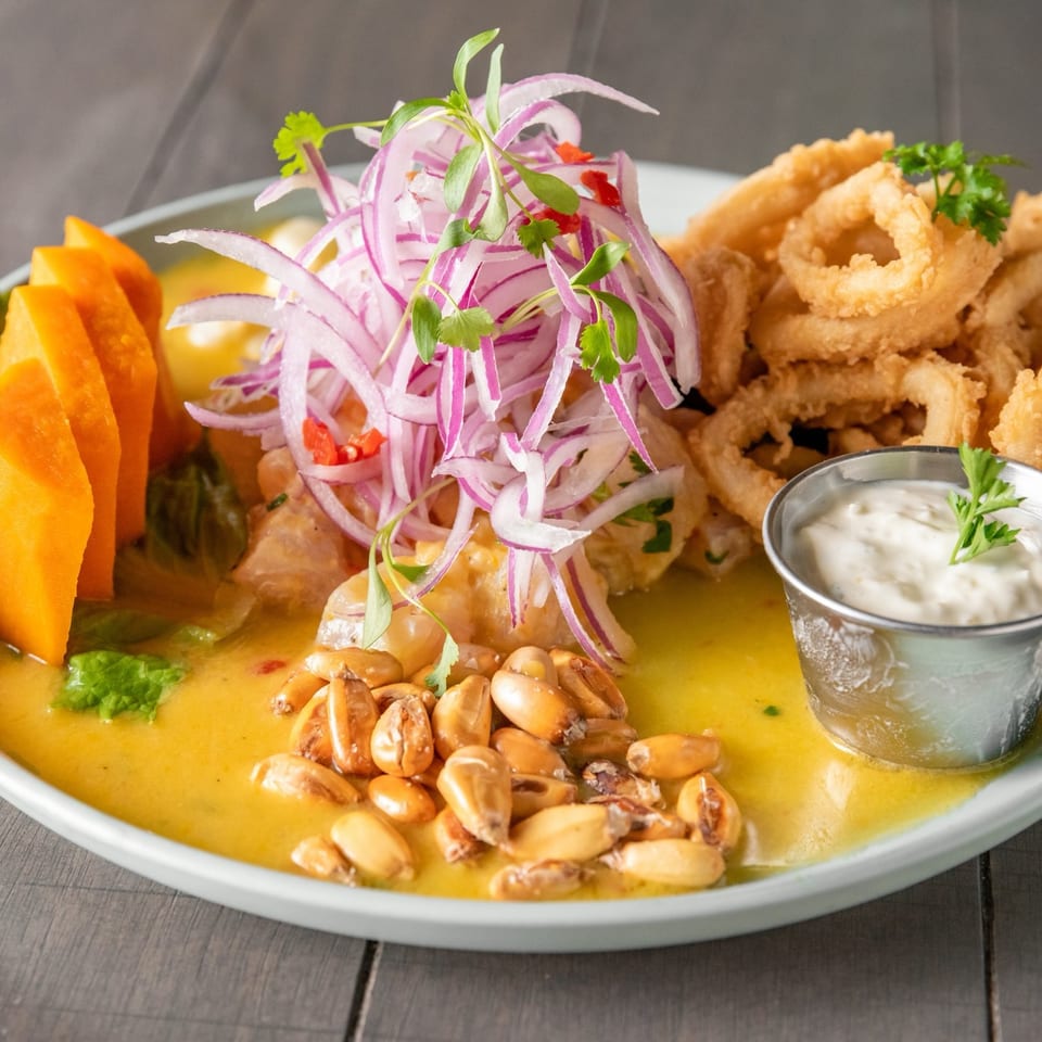 Platter of golden curry topped with peanuts and red onions, served with fried calamari, vegetables, herbs, and dipping sauce.